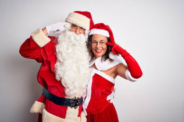 Orta yaşlı çift, Noel Baba kostümü giyip izole edilmiş beyaz arka planda sarılıyorlar. Tek parmakla gülümsüyorlar, harika bir fikir ya da düşünce, iyi bir hafıza.