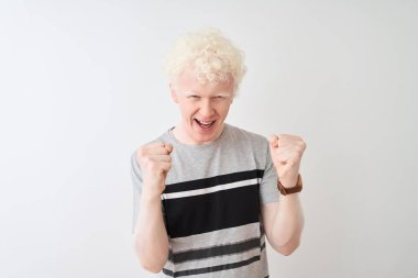 Genç albino sarışın adam rahat t-shirt izole beyaz arka plan üzerinde ayakta giyen deli ve silah kaldırdı ve kapalı gözleri heyecanlı çığlık ile başarı için deli kutluyor. Kazanan kavramı