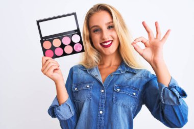 Güzel, sarışın bir kadın makyajlı, izole beyaz arka planda duruyor. Tamam işareti yapıyor. Parmaklarıyla, mükemmel bir sembol.