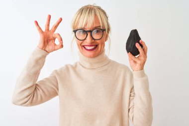 İzole edilmiş beyaz arka plan üzerinde avokado tutan orta yaşlı kadın tamam işareti yapıyor, mükemmel bir sembol.