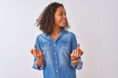 İzole edilmiş beyaz arka planda duran kot gömlekli genç Brezilyalı kadın orta parmağını göstererek kötü ifade, provokasyon ve kaba tavır sergiliyor. Heyecanlı çığlık