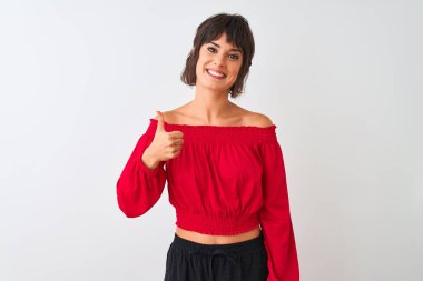 Kırmızı yaz tişörtü giyen genç ve güzel bir kadın izole edilmiş beyaz arka planda durup mutlu bir el hareketi yapıyor. Kameraya bakıp başarıyı gösteren ifade onaylanıyor.