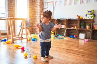 Güzel çocuk, kreşte ayakta alkışlıyor ve gülümsüyor.