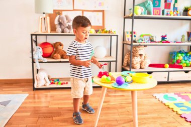 Anaokulunda plastik tabaklar, meyveler ve sebzelerle oynayan güzel bir çocuk.