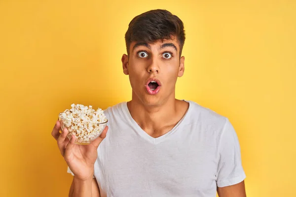 Jovem Indiano Segurando Pacote Pipocas Sobre Fundo Amarelo Isolado Assustado — Fotografia de Stock