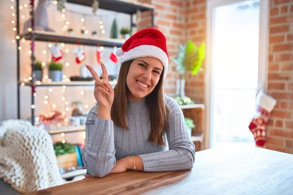 Joven Hermosa Mujer Con Sombrero Navidad Sentado Mesa Casa Sonriendo — Foto de Stock