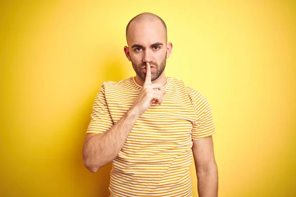 턱수염을 기르고 노란색외진 티셔츠를 대머리 남자는 입술에 손가락을 조용히 있기를 — 스톡 사진