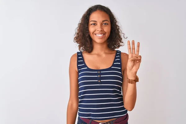白い背景の上にストライプのTシャツを着た若いブラジル人女性が顔を出し 自信と幸せを笑顔で3番目の指で指差す — ストック写真