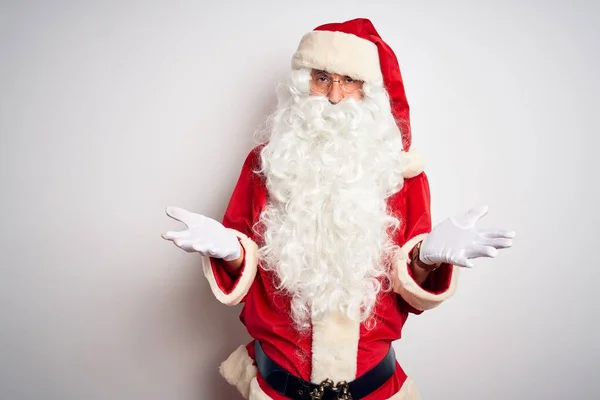 中年英俊男子身穿圣诞老人服装 站在孤独的白色背景之上 毫无头绪 与张开的双臂混淆不清 没有概念 — 图库照片