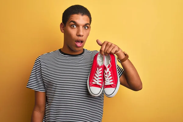 Jovem Árabe Bonito Homem Segurando Tênis Casuais Sobre Fundo Amarelo — Fotografia de Stock