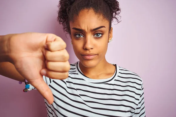 African american woman wearing navy striped t-shirt standing over isolated pink background with angry face, negative sign showing dislike with thumbs down, rejection concept