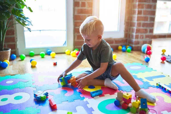 Joven niño caucásico jugando en el jardín de infantes con juguetes. Preescolar — Foto de Stock