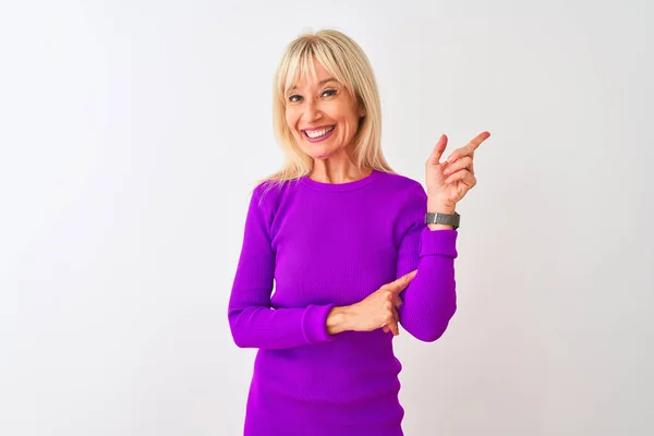 stock image Middle age woman wearing purple t-shirt standing over isolated white background with a big smile on face, pointing with hand and finger to the side looking at the camera.