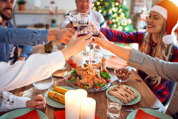 サンタの帽子をかぶっている美しい家族は笑顔で自信を持っています 自宅でクリスマスを祝うワインのカップとロースト七面鳥のトーストを食べる — ストック写真