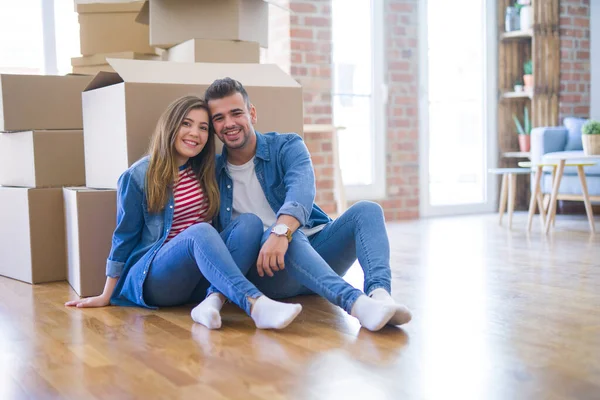 Joven hermosa pareja en el amor de mudarse a nuevo hogar, sentado en th — Foto de Stock