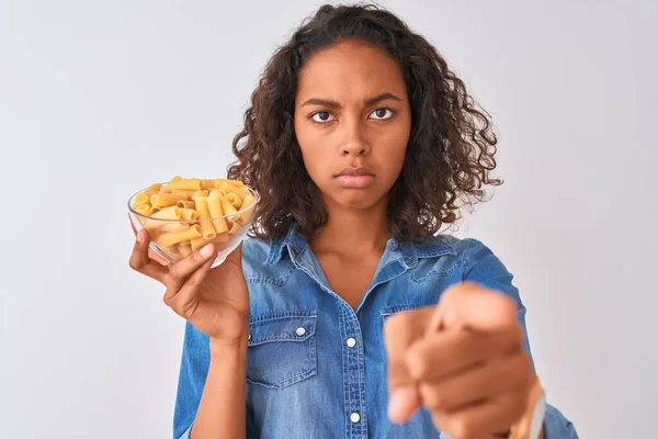 若いですブラジル人女性保持ボウルとともにマカロニパスタ上の隔離された白い背景指差しで指でカメラとあなたに 手のサイン 正とフロントから自信を持ってジェスチャー — ストック写真