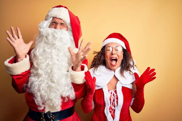 Paar Mittleren Alters Weihnachtsmannkostüm Und Brille Vor Isoliertem Gelben Hintergrund — Stockfoto