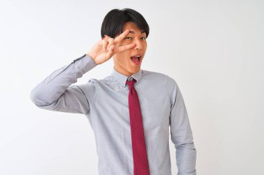 Soyutlanmış beyaz arka planda duran zarif bir kravat takan Çinli işadamı, barış sembolü yapıyor, parmaklarının üzerinde gülümseyerek zaferi gösteriyor.