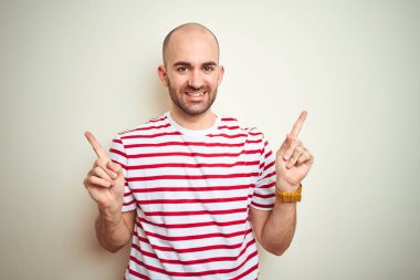 Sakallı, beyaz izole edilmiş arka planda sıradan kırmızı tişörtler giyen, kendine güvenen, farklı yönleri gösteren genç, kel bir adam. Reklam için boşluk kopyala