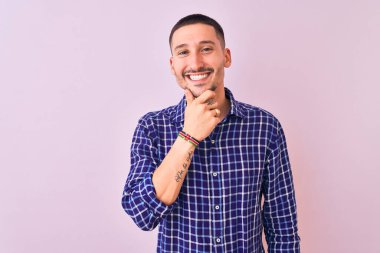 İzole edilmiş arka planda duran yakışıklı genç adam kameraya bakarak kollarını kavuşturup gülümseyerek çenesini kaldırdı. Olumlu düşünüyorum..