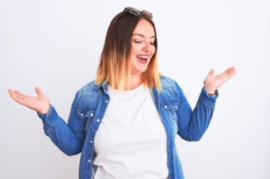 İzole edilmiş beyaz arka plan üzerinde duran kot gömlekli güzel bir kadın gülümseyerek iki elini de açık tutuyor, sunuyor ve reklam karşılaştırması yapıyor ve dengeyi sağlıyor.