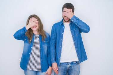 Genç ve güzel bir çift, izole edilmiş beyaz bir arka planda el ele gülüyor ve şaşkınlıkla gözleri örtüyor. Kör kavram.