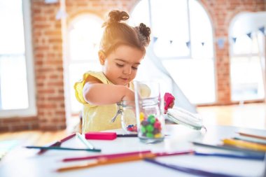 Anaokulunun masasında çikolata renkli toplarla oynayan güzel çocuk.