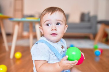 Anaokulunda küçük renkli toplarla oynayan güzel bir çocuk.