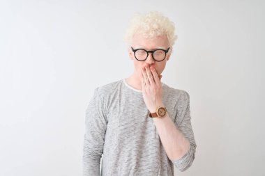 İzole edilmiş beyaz arka planda çizgili tişört ve gözlük takan genç, sarışın adam esnemekten sıkılmış, ağzı eliyle kapatmaktan sıkılmış. Huzursuz ve uykulu..