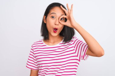 İzole edilmiş beyaz arka plan üzerinde duran çizgili tişört giyen genç Çinli kadın şaşırmış yüz ifadesiyle şaşırmış, parmaklarından bakan bir hareket yapıyor. İnançsız ifade.