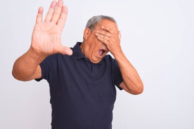 Siyah polo giyen yaşlı gri saçlı adam izole edilmiş beyaz arka planda duruyor gözleri ellerle kaplıyor ve üzgün ve korku ifadesiyle dur hareketi yapıyor. Utanç verici ve olumsuz bir kavram..