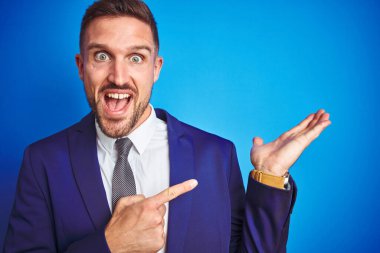 Yakından bakınca mavi izole edilmiş arka planda genç bir iş adamının resmi hayrete düşmüş ve kameraya gülümserken eliyle ve parmağıyla işaret ediyor..