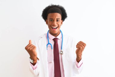 İzole edilmiş beyaz arka plan üzerinde setoskop takan genç Afrikalı Amerikalı doktor kollarını kaldırarak ve açık gözlerle başarının şaşkınlığını ve şaşkınlığını kutluyor. Kazanan konsept.