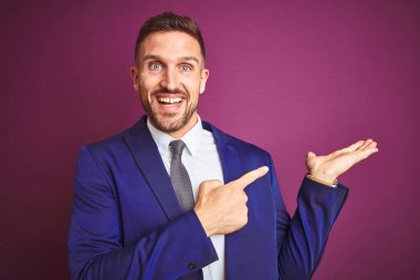 Mor izole edilmiş arka planda genç yakışıklı iş adamı kameraya hayret ediyor ve gülümsüyor..