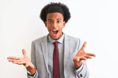 Genç Afro-Amerikalı iş adamı takım elbise giyip izole edilmiş beyaz arka planda duruyor. Çılgınlığı kutluyor ve başarıyı kollarını kaldırıp heyecanla haykırarak haykırıyor. Kazanan konsept