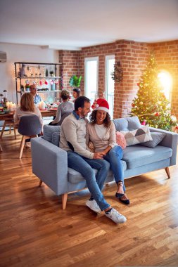 Noel arifesini evde geleneksel yemek ve dekorasyonla kutlayan aile ve arkadaşlar kanepede oturup romantik yaşlı çiftler gibi sohbet ediyorlar.