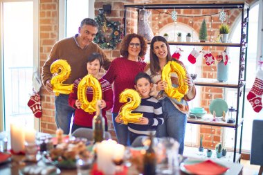 Mutlu ve kendinden emin gülümseyen güzel bir aile. Ayakta durup poz vererek 2020 balonu evde yeni yılı kutluyoruz.