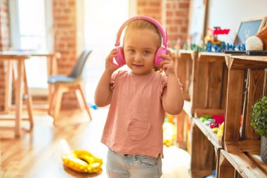 Anaokulunda kulaklık takıp müzik dinleyen güzel sarışın kız.