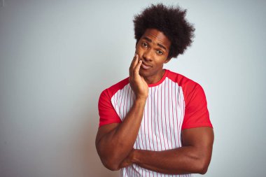 Afro saçlı, kırmızı çizgili tişörtlü, izole edilmiş beyaz arka planı olan, yorgun ve bunalımlı, kolları çaprazlanmış Afro-Amerikan bir adam..