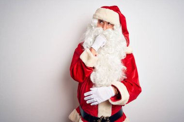 Orta yaşlı, yakışıklı, Noel Baba kostümü giymiş beyaz arka plan üzerinde duran bir adam bir soru hakkında endişeli ve gergin bir şekilde düşünüyor.