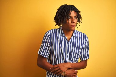 Rasta desenli tişörtlü Afro adam izole edilmiş sarı arka planda mide bulantısı, acı verici bir hastalık yüzünden el üstünde. Ache kavramı.