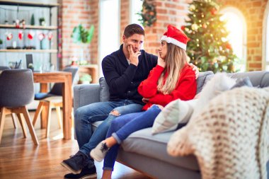 Noel Baba şapkası takan genç bir çift evdeki Noel ağacının etrafında oturmuş kollarını kavuşturup depresyondan sıkılmış ve yorgun göründüklerini düşünüyorlar..