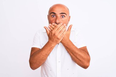 Middle age handsome man wearing elegant shirt standing over isolated white background shocked covering mouth with hands for mistake. Secret concept.