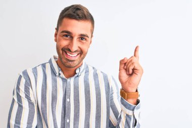 Soyutlanmış arka planda zarif gömlekler giyen yakışıklı bir iş adamı. Yüzünde kocaman bir gülümseme, eli ve parmağı kameraya bakıyor..