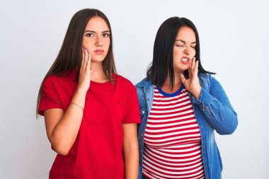 İzole edilmiş beyaz arka planda dikilen gündelik kıyafetler giyen genç ve güzel kadınlar diş ağrısı ya da diş hastalığından dolayı ağızlarına acı dolu bir ifadeyle dokunuyorlar. Dişçi konsepti.