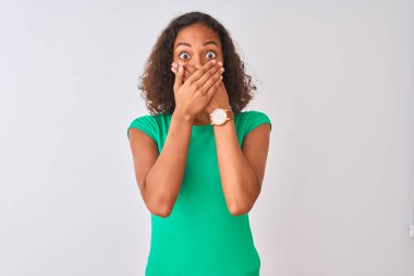 İzole edilmiş beyaz arka planda duran yeşil tişörtlü genç Brezilyalı kadın yanlışlıkla ağızlarını kapatarak şok geçirdi. Gizli konsept.
