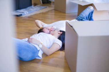 Genç güzel çift karton kutular etrafında yeni evde yatarken