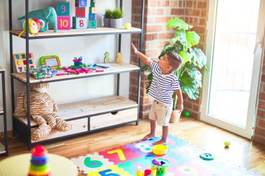 Anaokulunda bir sürü oyuncakla bekleyen güzel bir çocuk.