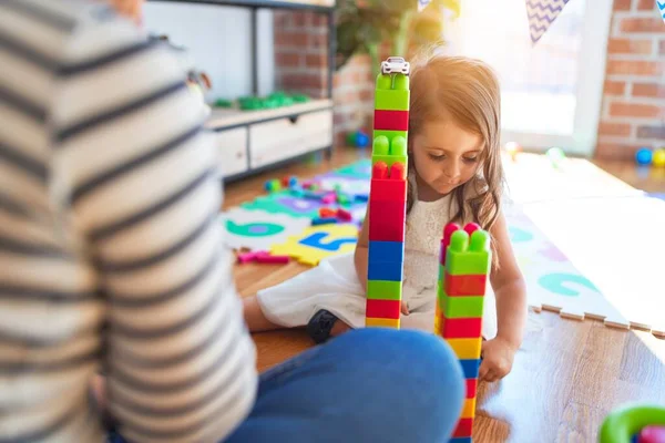 Красива Вчителька Малюк Грають Будівельними Блоками Навколо Багатьох Іграшок Дитячому — стокове фото