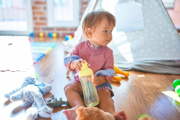 Adorable Niño Pequeño Sosteniendo Biberón Alrededor Muchos Juguetes Jardín Infantes — Foto de Stock